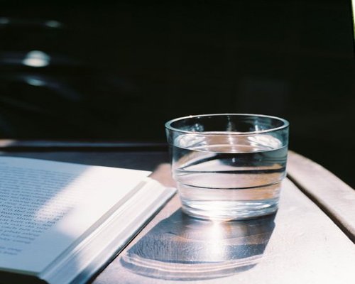 A glass of water and an open book on a clean table representing a quiet pause