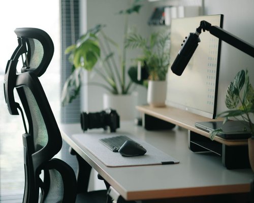 A well-lit, organized home office desk with an ergonomic chair