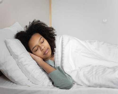 Person sleeping peacefully in a comfortable bed with soft linens